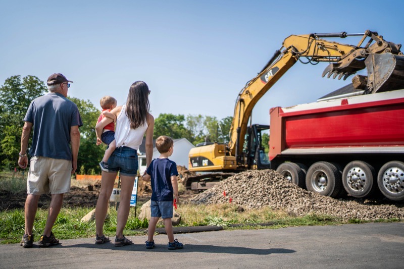Family watching excavation begin on their new custom home build site