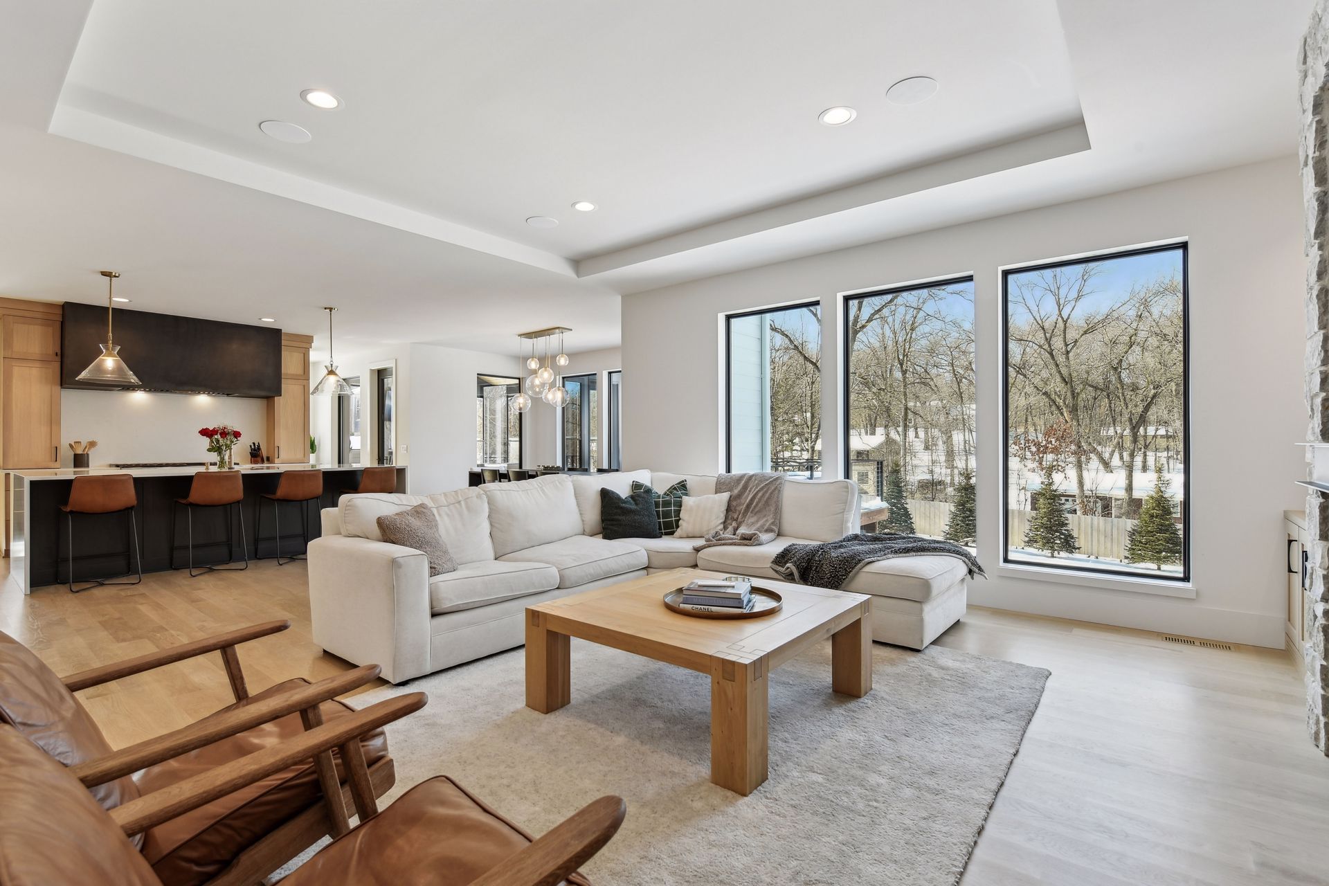Open concept great room with kitchen island, tray ceiling and floor-to-ceiling windows