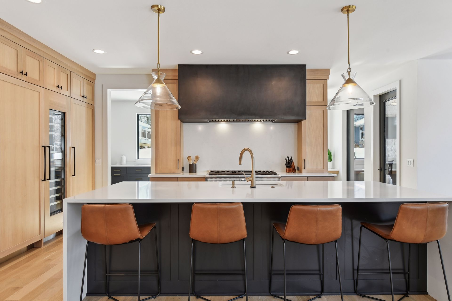 Kitchen island with quartz countertop, leather stools and glass pendant lights