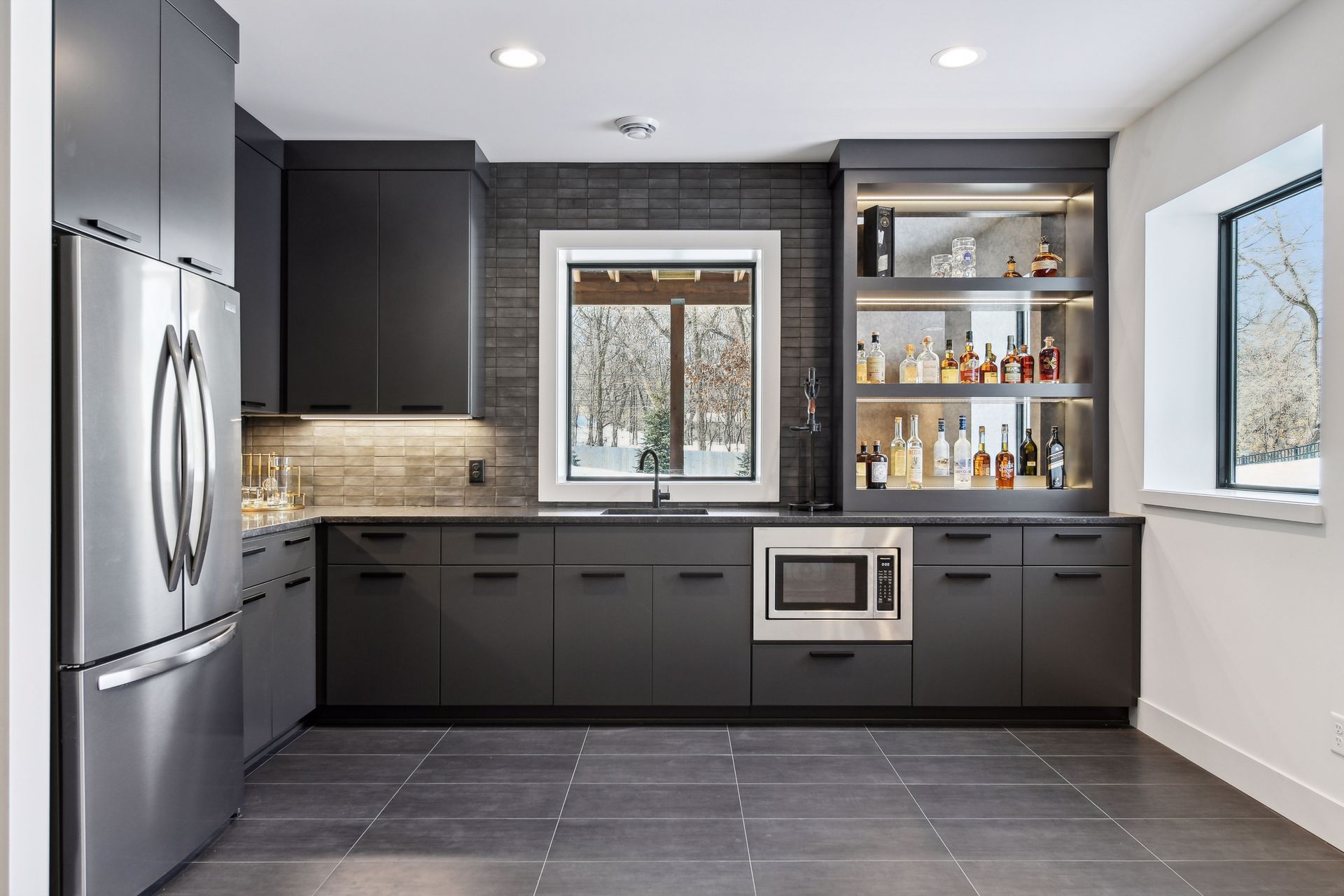 Custom wet bar with dark cabinetry, LED-lit shelving and tile backsplash